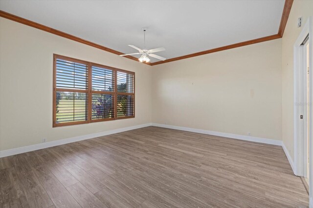 spare room with a ceiling fan, crown molding, baseboards, and wood finished floors