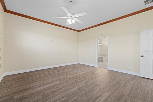 empty room with visible vents, wood finished floors, baseboards, and ornamental molding