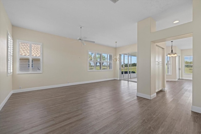 empty room featuring baseboards, a healthy amount of sunlight, and dark wood finished floors