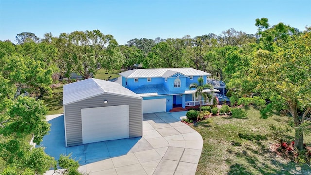 view of front of property with a garage, a front lawn, driveway, covered porch, and metal roof