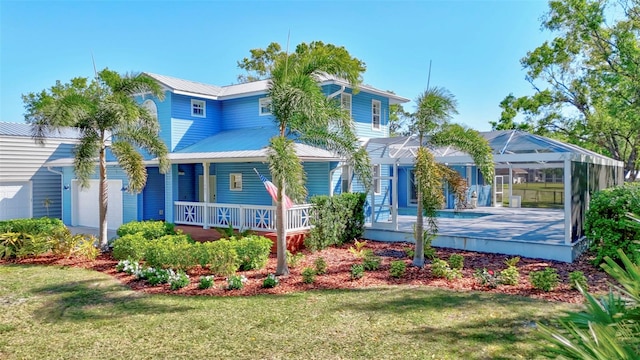 exterior space featuring a front lawn, a swimming pool, covered porch, an attached garage, and a lanai