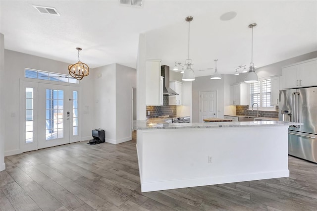 kitchen with visible vents, appliances with stainless steel finishes, wall chimney exhaust hood, and wood finished floors