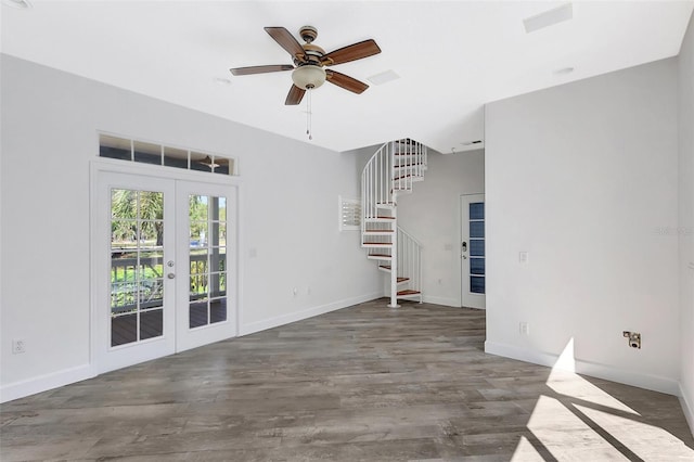 unfurnished living room featuring baseboards, stairs, french doors, wood finished floors, and a ceiling fan