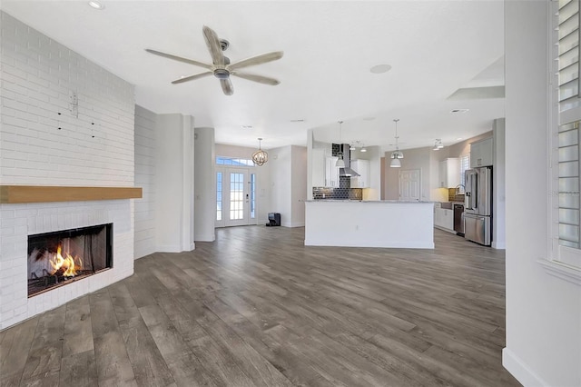 unfurnished living room featuring baseboards, a brick fireplace, and dark wood-style floors