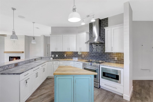 kitchen featuring tasteful backsplash, butcher block countertops, appliances with stainless steel finishes, wood finished floors, and wall chimney exhaust hood