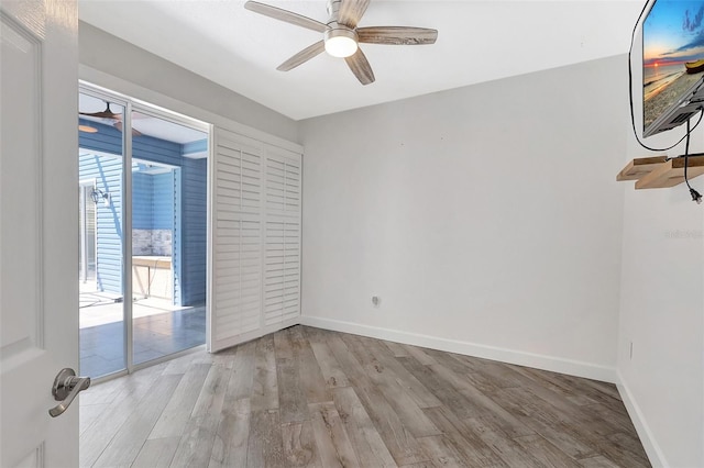 spare room with baseboards, light wood-style floors, and ceiling fan