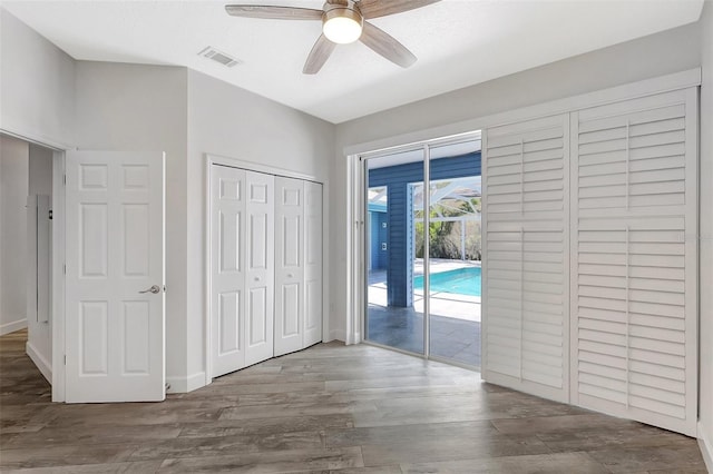 unfurnished bedroom featuring access to outside, wood finished floors, visible vents, and ceiling fan