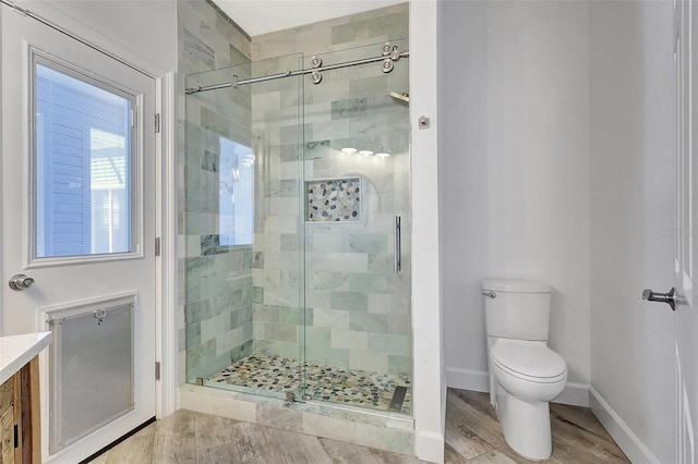 bathroom featuring a shower stall, toilet, baseboards, and wood finished floors