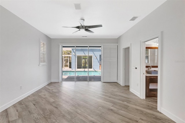 spare room with baseboards, visible vents, light wood finished floors, and a sink