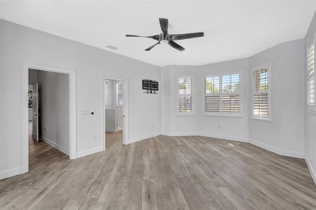 interior space with light wood-style flooring, multiple windows, baseboards, and visible vents