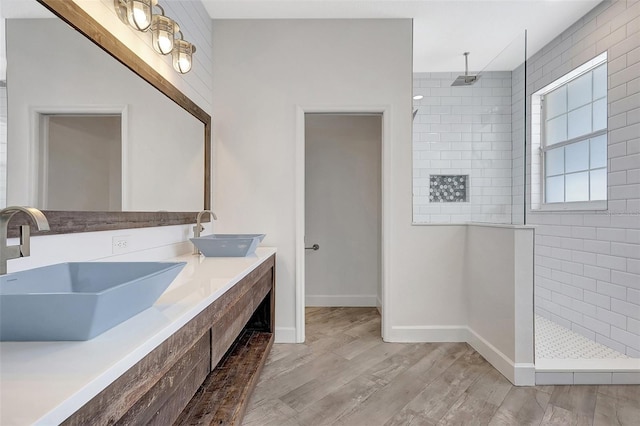 bathroom featuring wood finished floors, walk in shower, and a sink