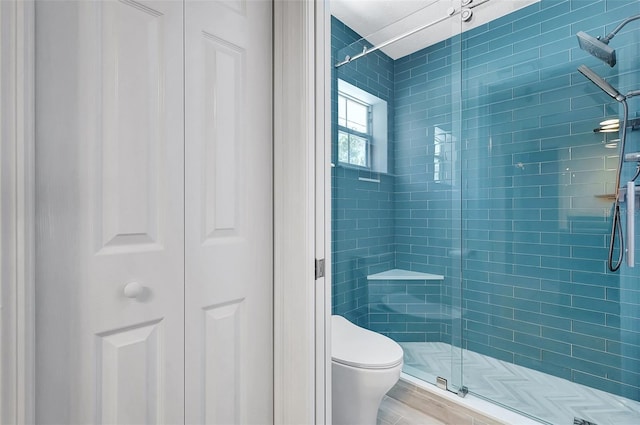 full bath featuring a shower stall, toilet, and a closet