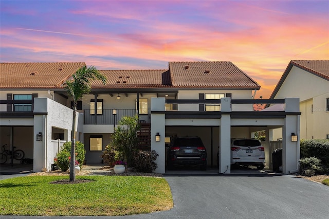 view of front of home with aphalt driveway, a carport, a tile roof, and stucco siding