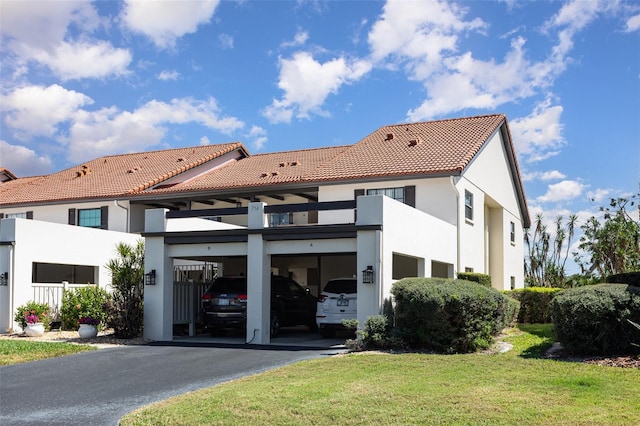 view of front of home featuring aphalt driveway, stucco siding, a front lawn, a garage, and a tile roof