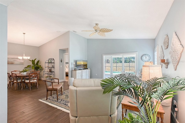 living area featuring dark wood finished floors, visible vents, ceiling fan with notable chandelier, and vaulted ceiling