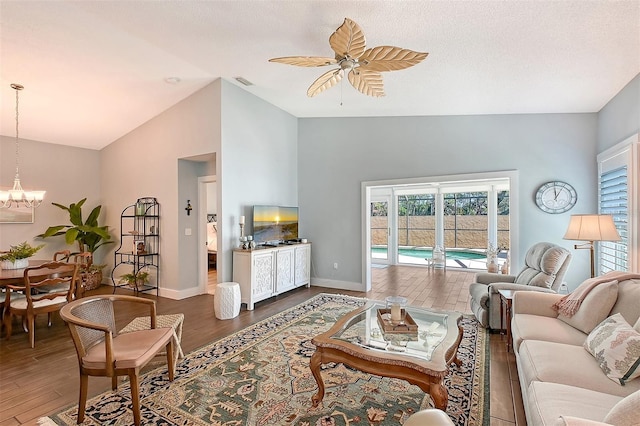 living area with baseboards, visible vents, dark wood finished floors, vaulted ceiling, and ceiling fan with notable chandelier