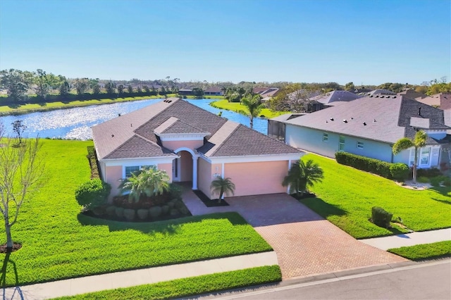 view of front facade featuring a water view, decorative driveway, a residential view, a front yard, and a garage