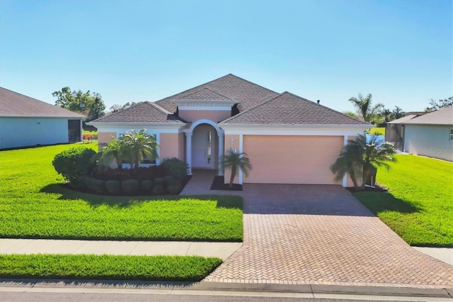 view of front of home with a front yard, decorative driveway, an attached garage, and stucco siding