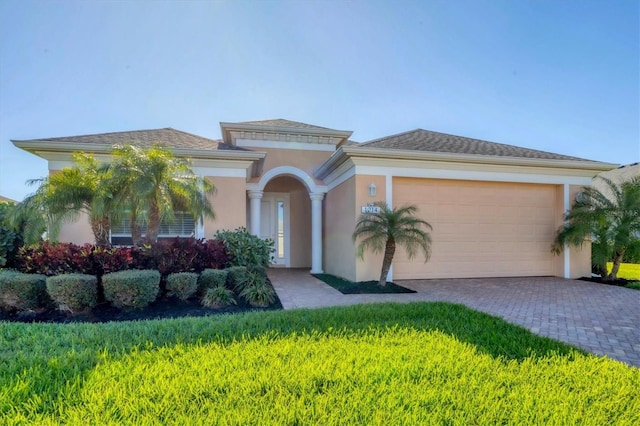 mediterranean / spanish-style home with stucco siding, decorative driveway, and a garage