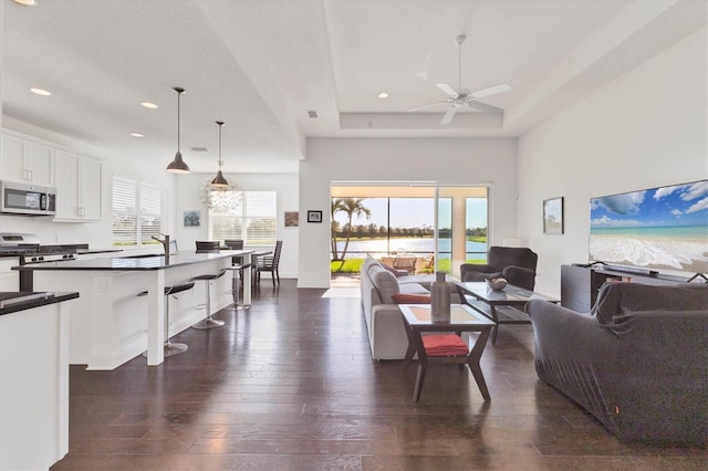 living area featuring visible vents, ceiling fan, dark wood finished floors, recessed lighting, and a raised ceiling