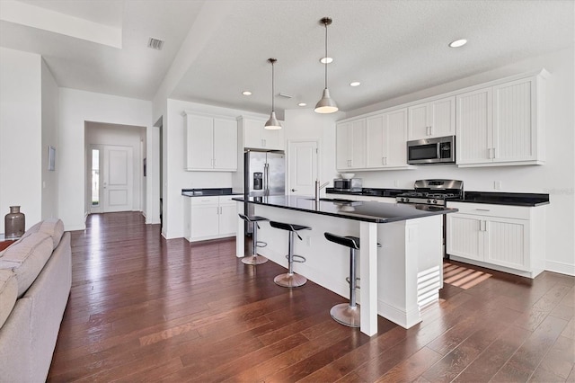 kitchen with dark wood finished floors, dark countertops, visible vents, and stainless steel appliances