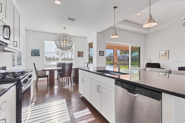 kitchen with a sink, dark countertops, dark wood-style flooring, and stainless steel appliances