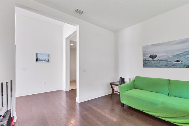 living area with visible vents, dark wood-style flooring, and baseboards