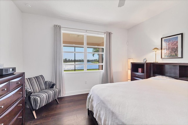 bedroom with ceiling fan, a water view, baseboards, and hardwood / wood-style flooring