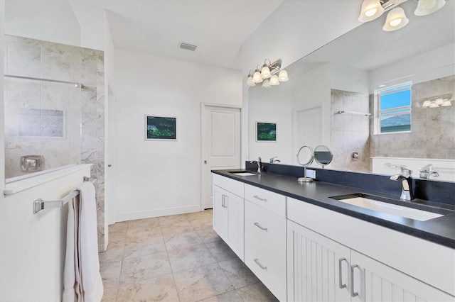 bathroom with double vanity, walk in shower, visible vents, and a sink