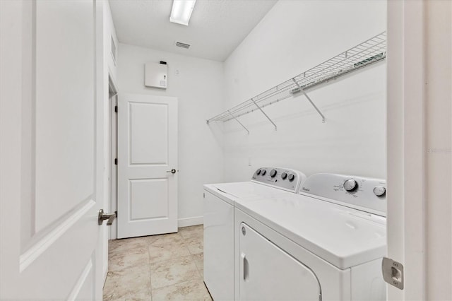 laundry area with laundry area, separate washer and dryer, visible vents, and baseboards