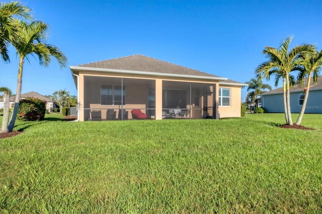 rear view of house with roof with shingles, a lawn, a sunroom, and stucco siding