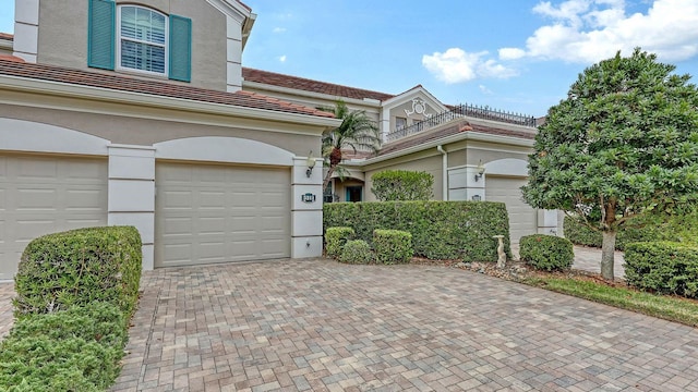 view of property with decorative driveway, a tile roof, and stucco siding