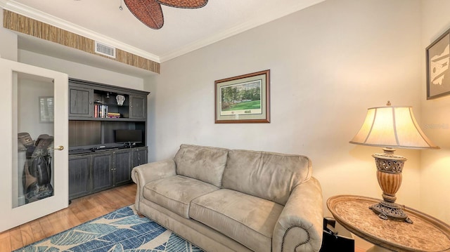 living area with ornamental molding, a ceiling fan, visible vents, and light wood-type flooring