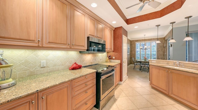 kitchen with ornamental molding, a sink, light stone counters, a tray ceiling, and stainless steel appliances