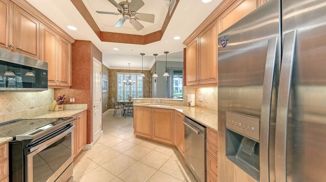 kitchen featuring crown molding, light stone countertops, a tray ceiling, appliances with stainless steel finishes, and a sink