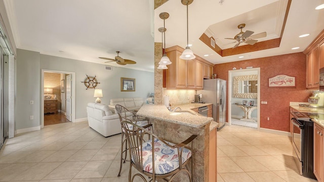 kitchen featuring a tray ceiling, light tile patterned flooring, appliances with stainless steel finishes, and ornamental molding