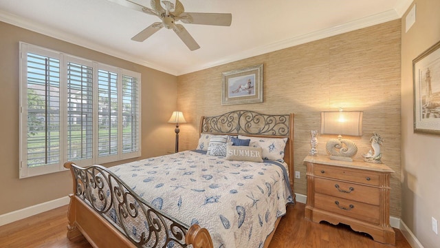 bedroom with a ceiling fan, crown molding, wood finished floors, and baseboards