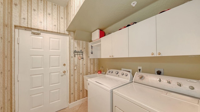 washroom featuring light tile patterned floors, washing machine and dryer, and cabinet space