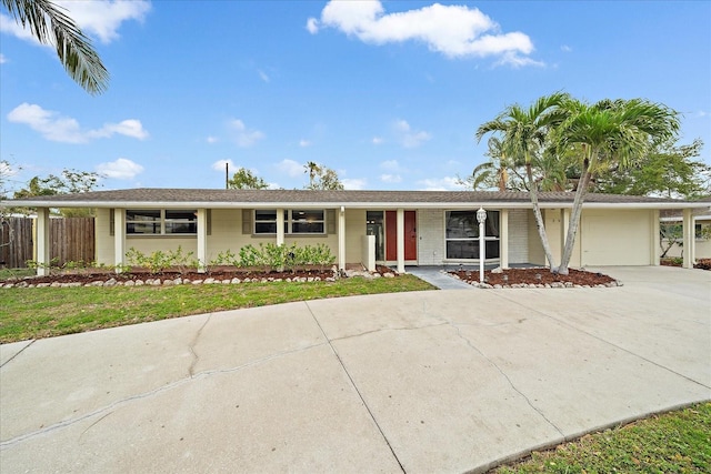 ranch-style home with brick siding, concrete driveway, a garage, and fence