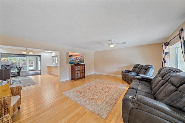 living room featuring hardwood / wood-style floors, ceiling fan, baseboards, and a textured ceiling