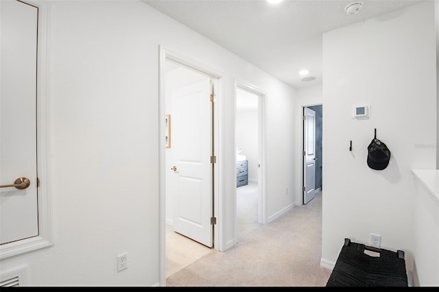 corridor featuring baseboards and light colored carpet