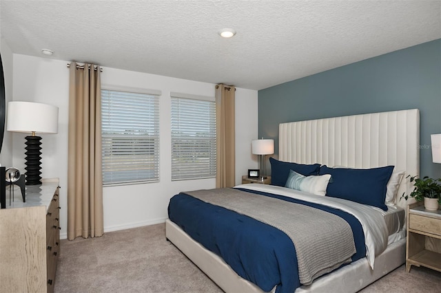 bedroom with light colored carpet, a textured ceiling, and baseboards