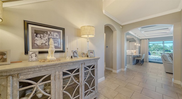 hall featuring arched walkways, light tile patterned floors, crown molding, and baseboards