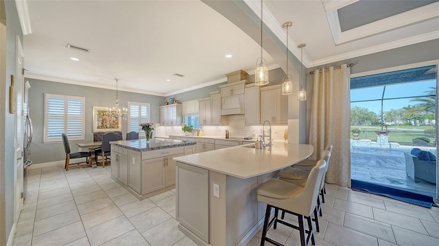 kitchen with tasteful backsplash, visible vents, a center island, crown molding, and a sink