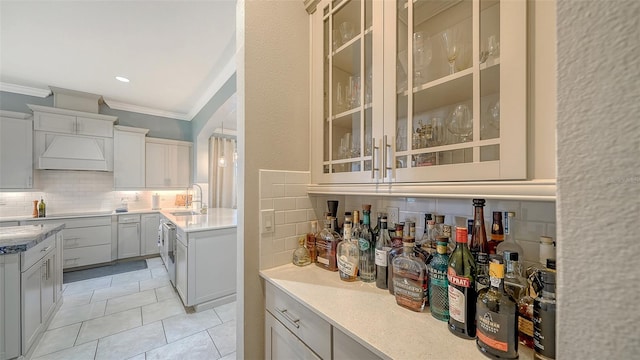 interior space featuring light tile patterned floors, premium range hood, a sink, decorative backsplash, and crown molding