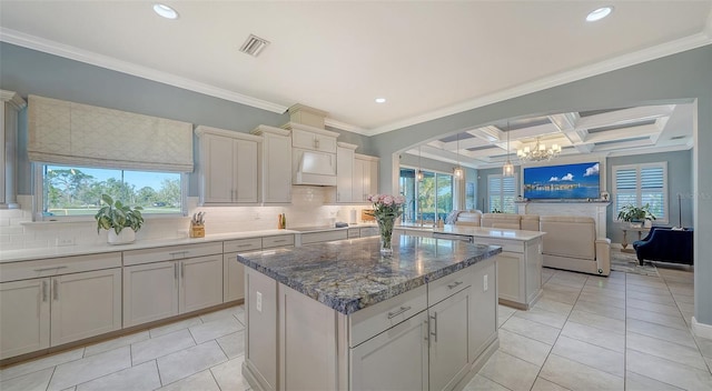 kitchen featuring premium range hood, visible vents, coffered ceiling, and backsplash