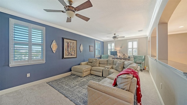 living room featuring visible vents, baseboards, carpet, ornamental molding, and a ceiling fan