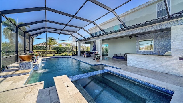 view of swimming pool featuring glass enclosure, a patio, a ceiling fan, a pool with connected hot tub, and outdoor dry bar