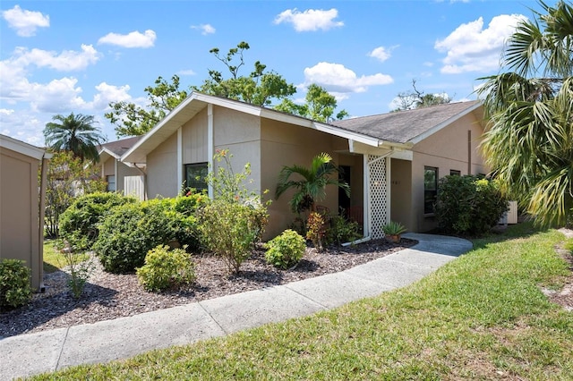 view of front of home featuring stucco siding and a front yard