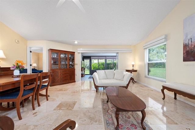 living room featuring lofted ceiling, baseboards, marble finish floor, and a textured ceiling